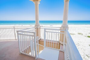 Un balcon avec des balustrades blanches donnant sur une plage.