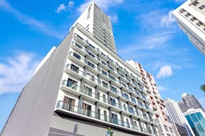 A high-rise building with multiple balconies and a clear sky. - Modern Studio with Balcony, Pool & Gym Access (Miami)