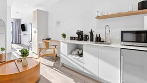 Et moderne køkken med mikrobølgeovn, kaffemaskine og en hylde med kopper.