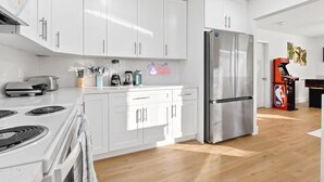 A modern kitchen with white cabinets, a stainless steel refrigerator, a coffee machine, and a microwave. - 4BR Oasis Near MIA - Jacuzzi - Games - BBQ (Miami)