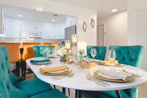 A dining area with teal upholstered chairs, a white table, and gold tableware. - 4BR Oasis Near MIA - Jacuzzi - Games - BBQ (Miami)