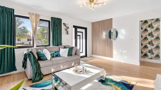 A modern living room with a sofa, coffee table, and artwork. - 4BR Oasis Near MIA - Jacuzzi - Games - BBQ (Miami)