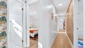 A hallway with a bed, wooden flooring, and a door with a leaf-patterned wallpaper. - 4BR Oasis Near MIA - Jacuzzi - Games - BBQ (Miami)