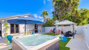 A backyard with a hot tub, a covered patio, and a play area. - 4BR Oasis Near MIA - Jacuzzi - Games - BBQ (Miami)
