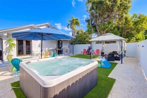 Ein Garten mit Whirlpool, überdachter Terrasse und Spielbereich.