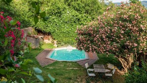 A backyard with a swimming pool, surrounded by lush greenery and flowering bushes. - Gîtes de la Soulondre: Vacation Home with Mountain View, Shared Pool, and Wi-Fi (Lodève)