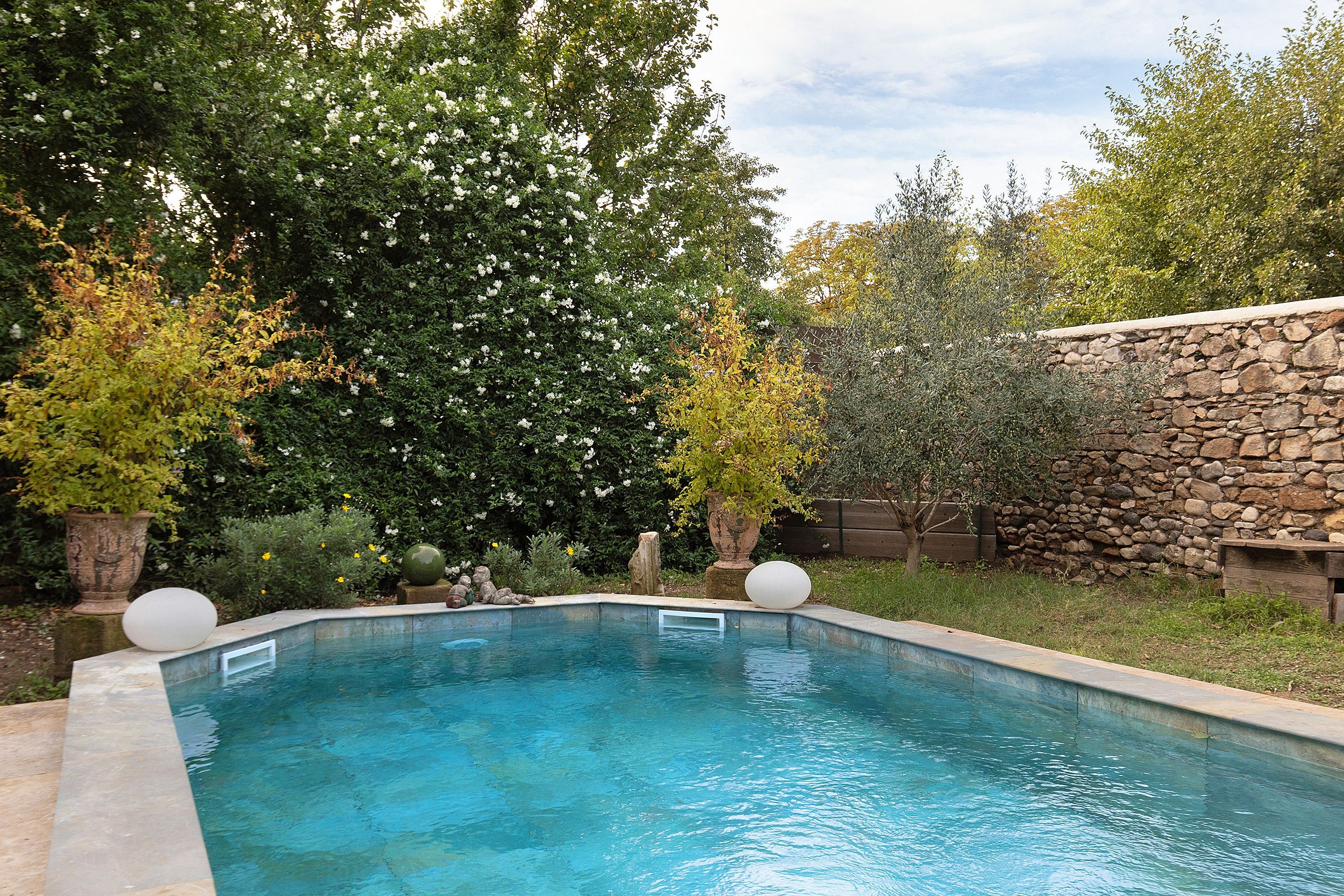 Ein Swimmingpool mit Steinmauer und Bäumen im Hintergrund.