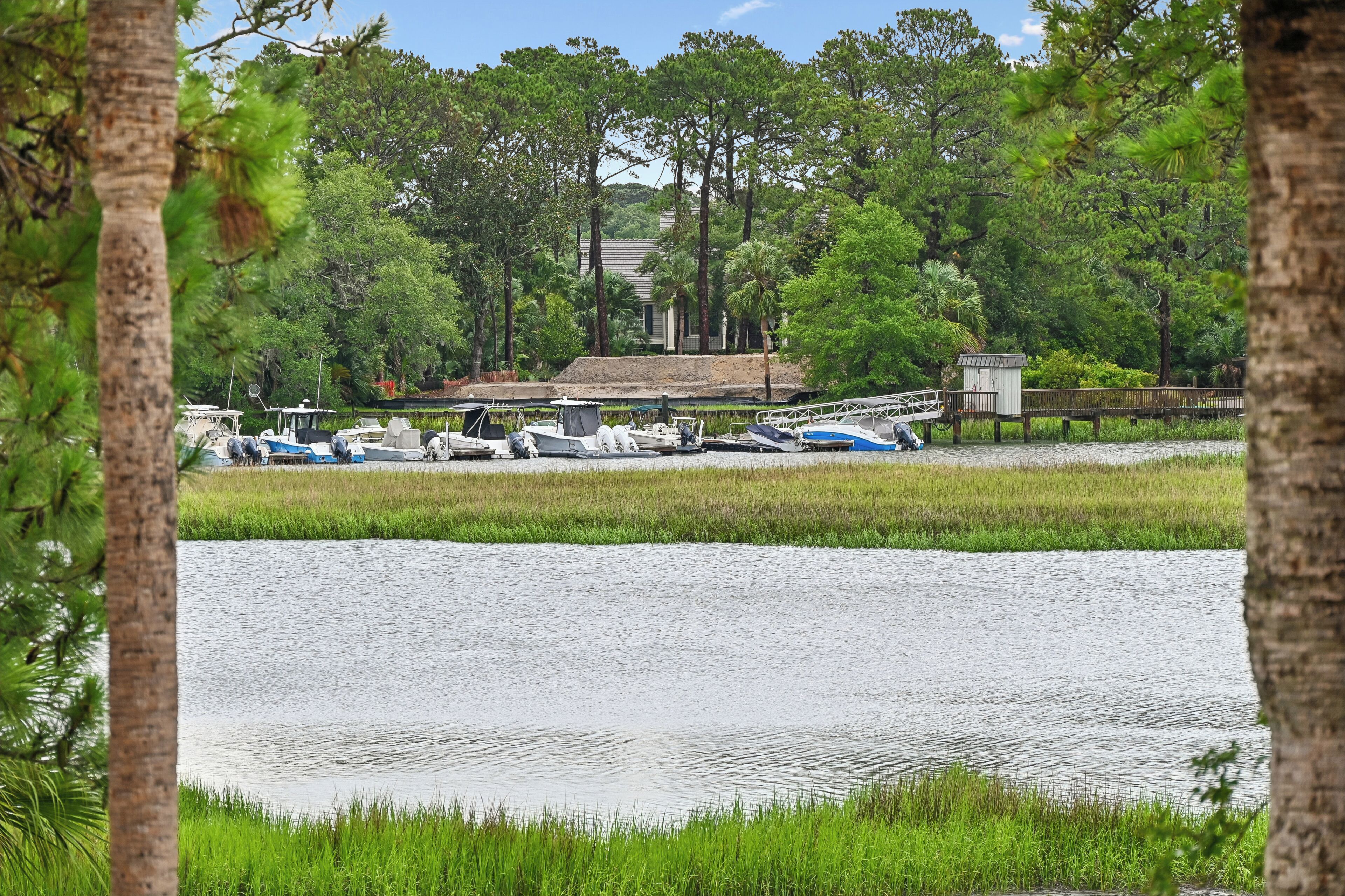 A tranquil water body with boats docked, surrounded by lush greenery and trees.