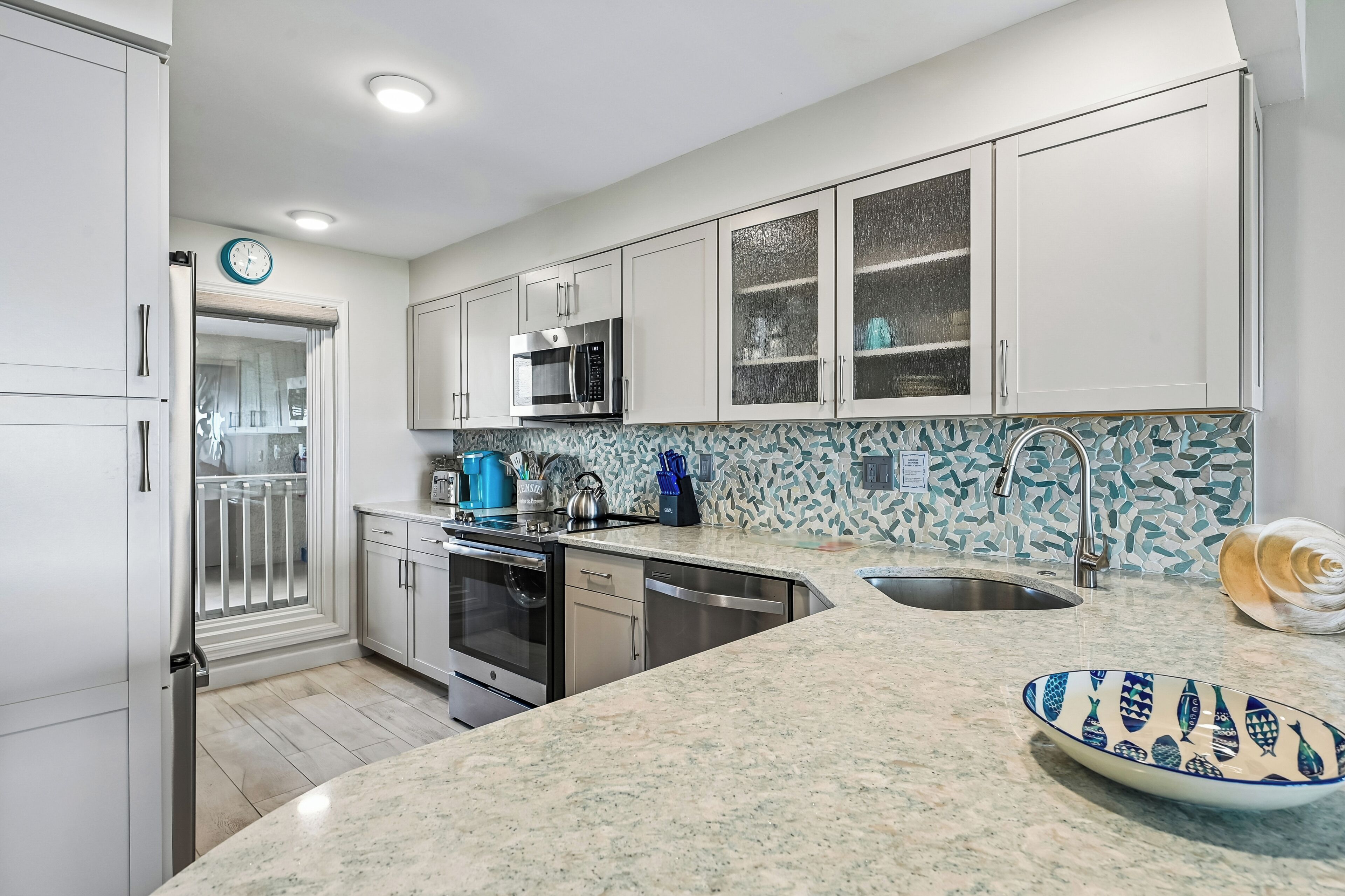 Una cocina moderna con gabinetes blancos, electrodomésticos de acero inoxidable, encimera de granito y un elegante salpicadero.