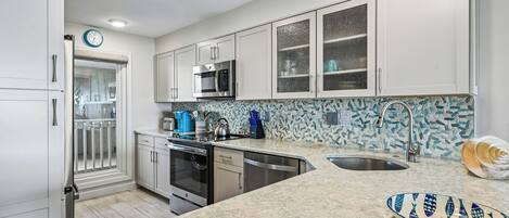 Una cocina moderna con gabinetes blancos, electrodomésticos de acero inoxidable, encimera de granito y un elegante salpicadero.