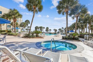 A pool area with lounge chairs, palm trees, and a building in the background. - Ocean Views and Resort Amenities (Hilton Head Island)