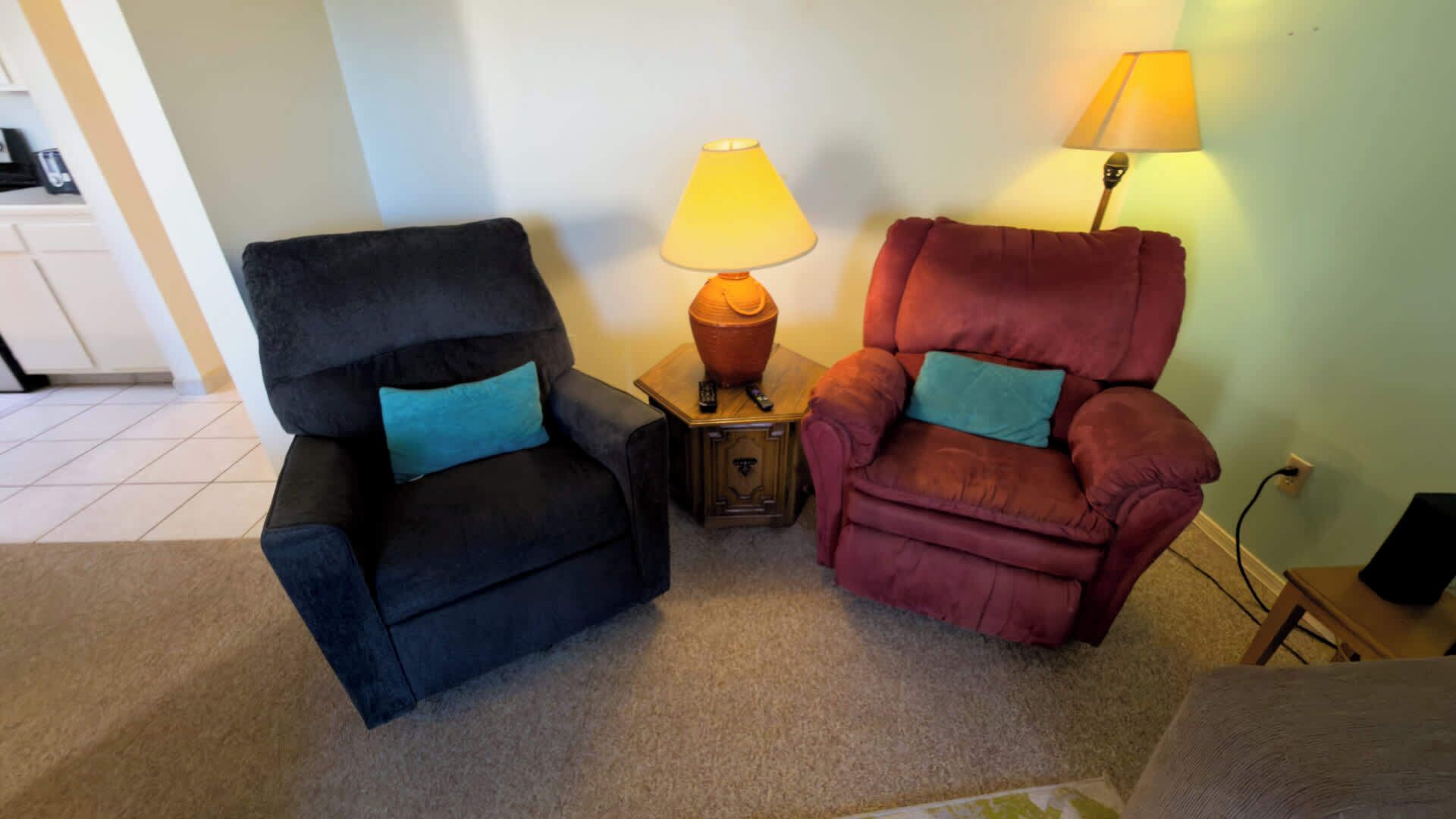 Dos sillones con lámparas, una mesita y un suelo alfombrado en una habitación.