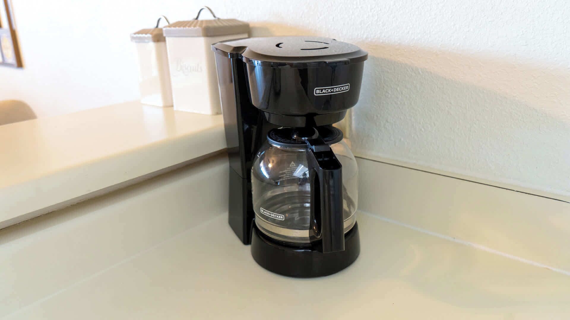 A black coffee maker on a white countertop.