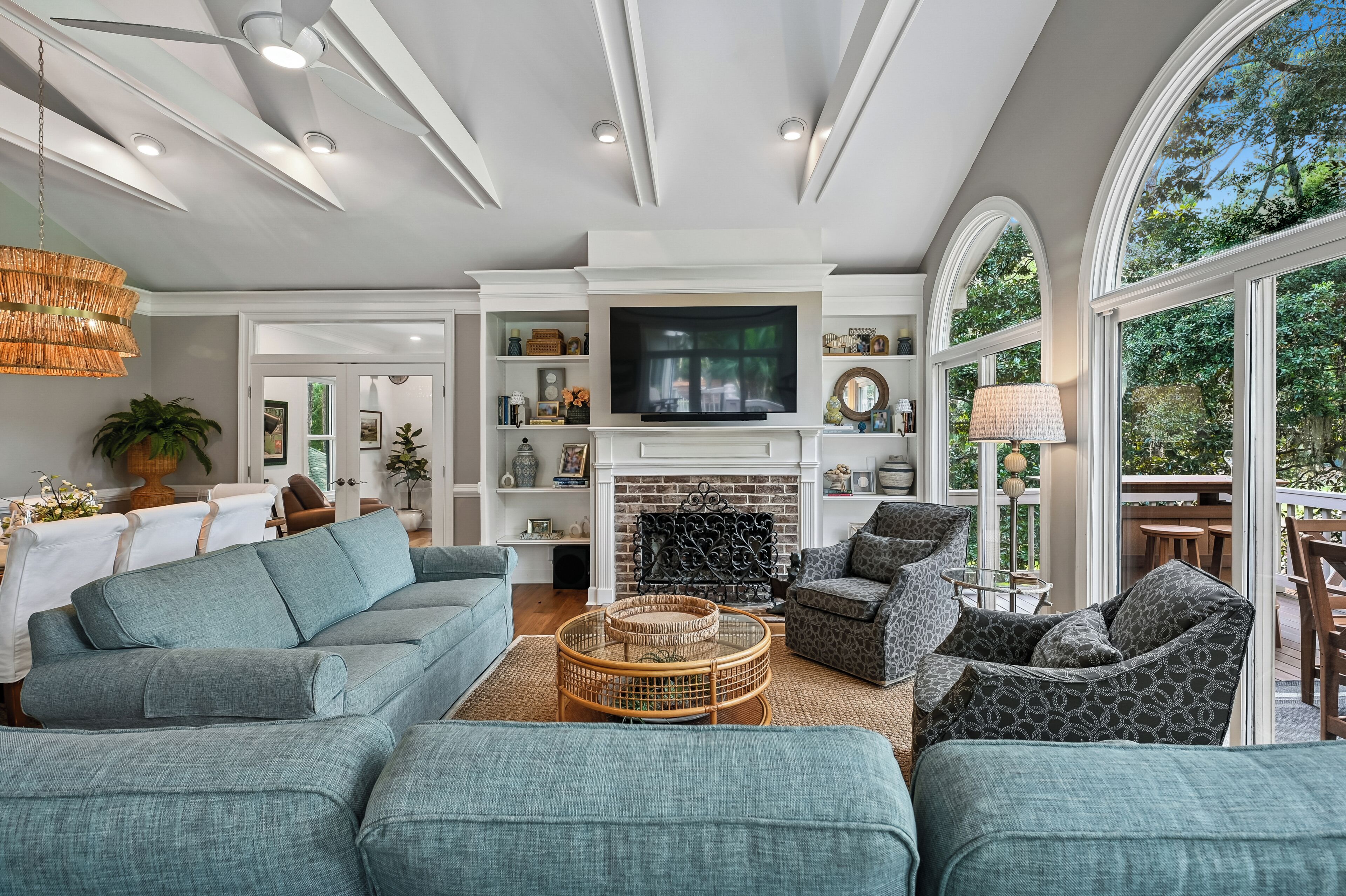 A modern living room with a fireplace, seating area, and large windows.