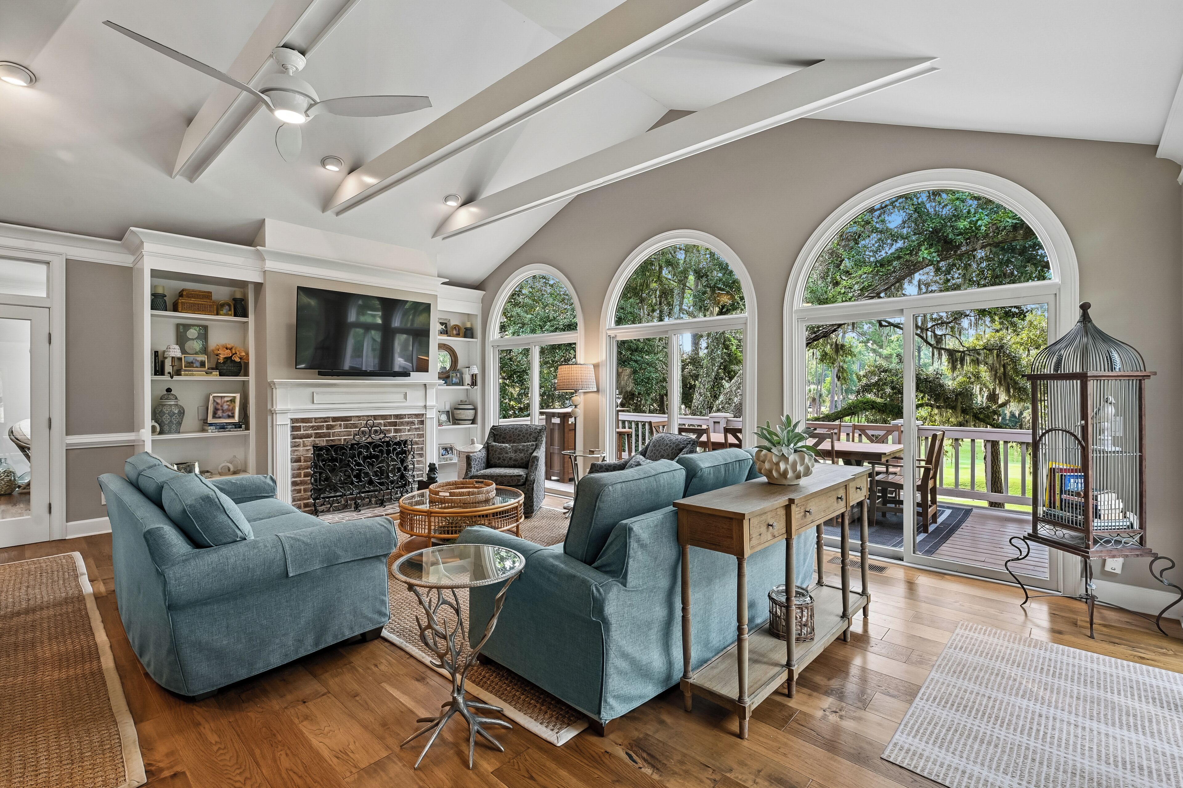 A spacious living room with a fireplace, comfortable seating, and large windows offering a view of the outdoors.