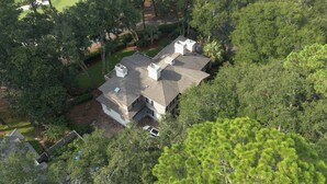A large house with multiple chimneys, surrounded by dense greenery and trees. - Sea Pines Home w/Views of Harbour Town Golf Course (Hilton Head Island)