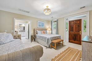 A bedroom with two beds, a wooden door, and a view of the kitchen. - Sea Pines Home w/Views of Harbour Town Golf Course (Hilton Head Island)