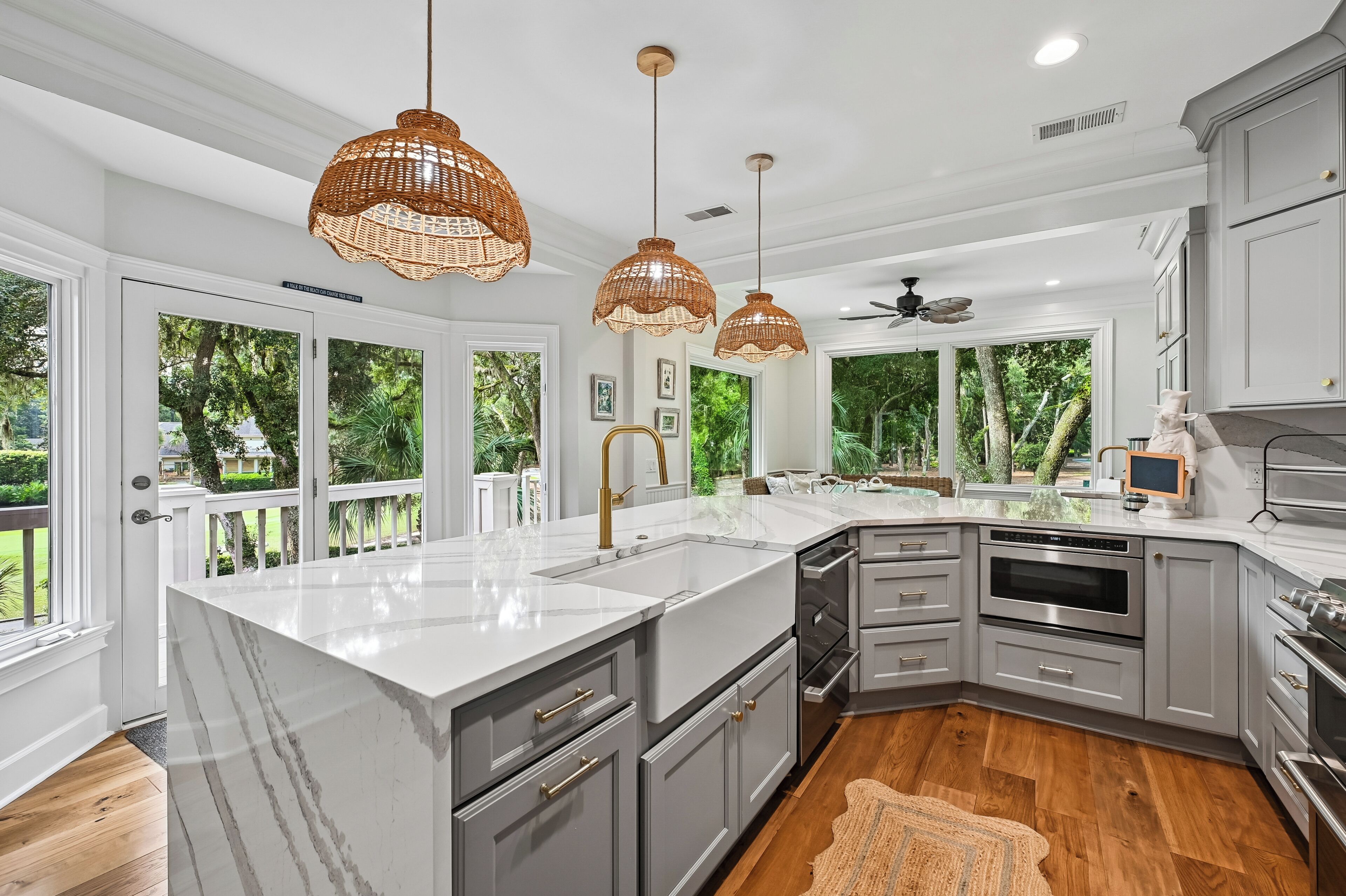 A modern kitchen with a large island, grey cabinetry, and a view of the outdoors.