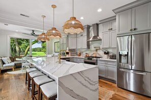 A modern kitchen with a central island, stainless steel appliances, and a view of a golf course. - Sea Pines Home w/Views of Harbour Town Golf Course (Hilton Head Island)