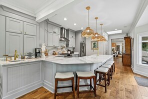 A kitchen with a large island, bar stools, pendant lighting, and a view into the dining area. - Sea Pines Home w/Views of Harbour Town Golf Course (Hilton Head Island)