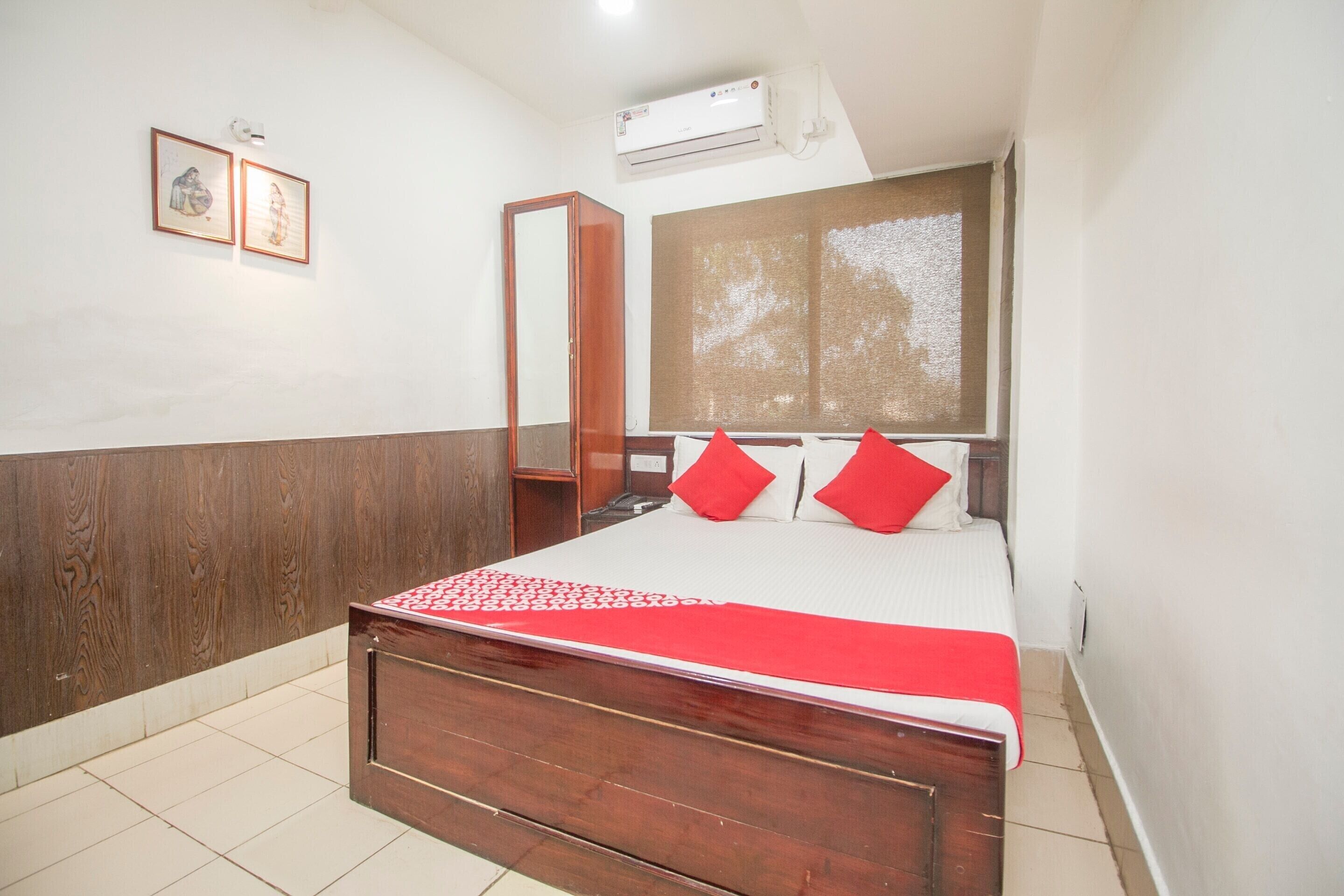 A bedroom with a wooden bed, a window with a view, and an air conditioning unit.
