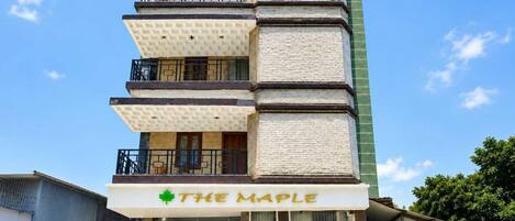 A multi-story building with a sign reading 'THE MAPLE' at the entrance.