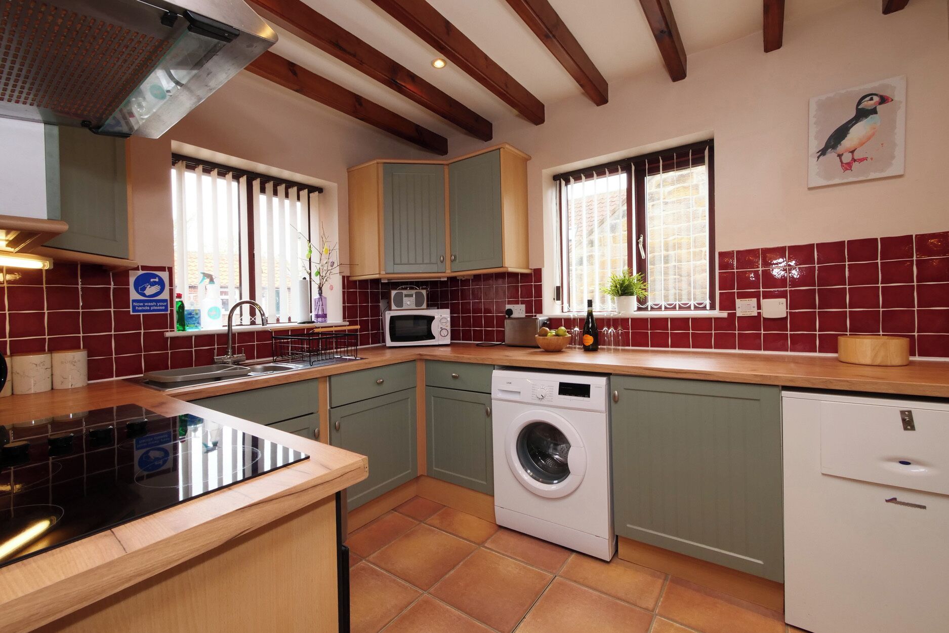 A kitchen with a washing machine, a microwave, and a sink.