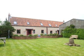 A two-story building with a tiled roof, a red door, and a sign that reads 'CHOLMEY.' - Scoresby Cottage @ Summerfield Farm (Whitby)