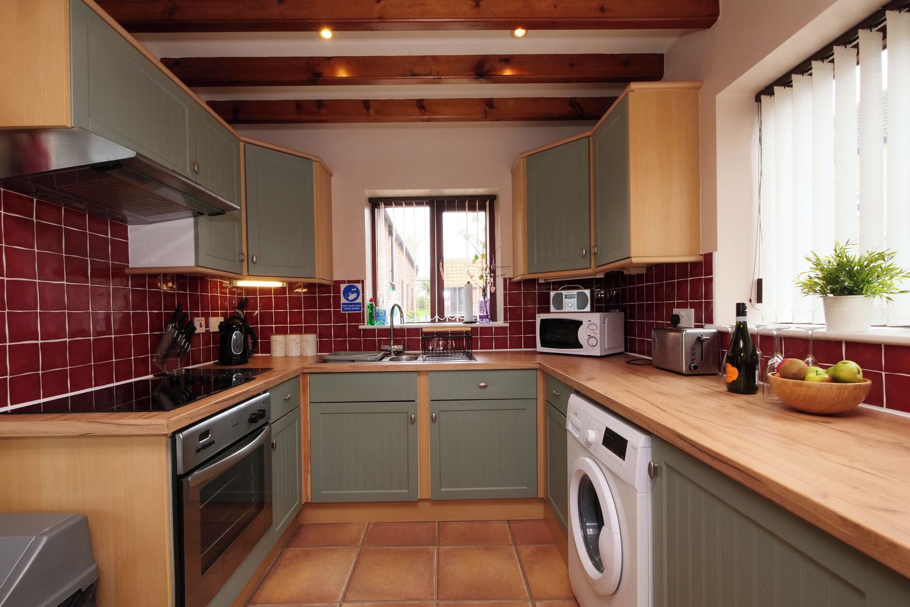 A compact kitchen with a washing machine, a microwave, and a toaster.
