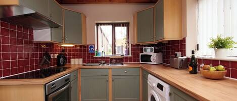 A compact kitchen with a washing machine, a microwave, and a toaster.