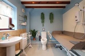 A bathroom with a sink, toilet, shower, and a bed. - Scoresby Cottage @ Summerfield Farm (Whitby)