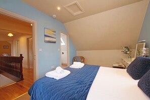 A bedroom with a bed, a chair, a desk, and a painting on the wall. - Scoresby Cottage @ Summerfield Farm (Whitby)