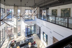 Eine moderne Hotelhalle mit hoher Decke, großen Fenstern und einer Galerieebene.
