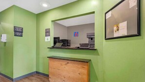 Un mostrador de recepción con una pared verde, una barra de madera y un cuadro enmarcado.