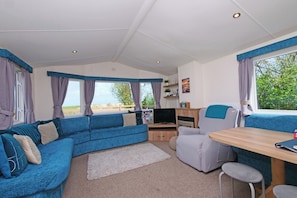 A cozy interior with a sofa, a table, and a TV. - Abbey View @ Summerfield Farm (Whitby)