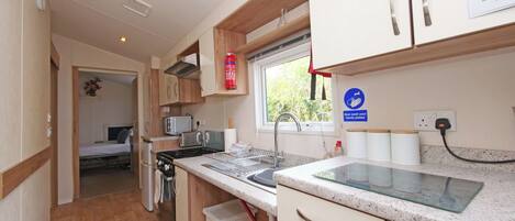 A compact kitchen with a stove, sink, and a window.