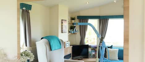 A room with a bed, a TV, a desk with a computer, a chair, and a window with curtains.