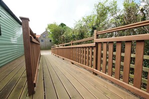A wooden deck with a railing, leading to a stone building with windows. - Abbey View @ Summerfield Farm (Whitby)