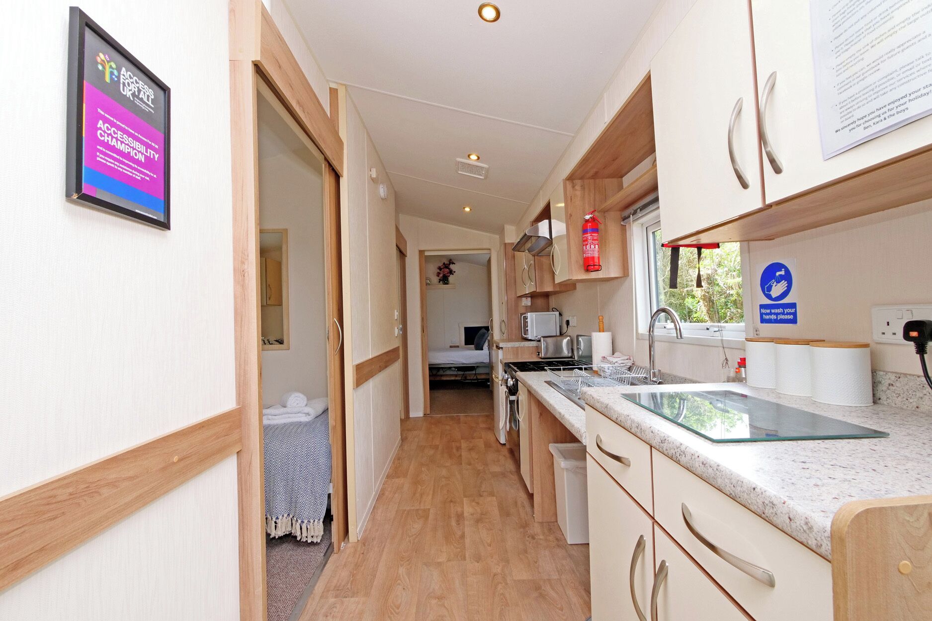 A narrow hallway leading to a compact kitchen with a sink, a toaster, and a stove.