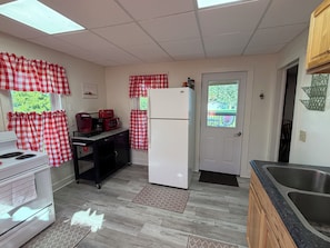 A kitchen with a white refrigerator, a stove, and a microwave on a black countertop.