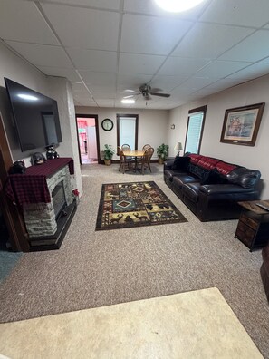 A living room with a fireplace, a television, a sofa, a coffee table, and a rug.
