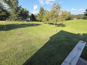A well-maintained grassy area with a wooden bench, trees, and a clear sky.