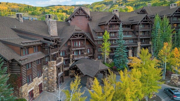 Un chalet composé de plusieurs bâtiments en bois, doté de cheminées en pierre et d’une cour centrale.