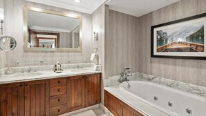 Une salle de bain moderne avec un grand miroir, un meuble-lavabo en bois, deux vasques et une baignoire îlot.