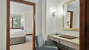 Une chambre d’hôtel avec un lit, un bureau, une chaise, un grand miroir et une fenêtre.