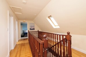 A hallway with wooden flooring, a staircase with a wooden railing, and a skylight. - Chomley @ Summerfield Farm (Whitby)