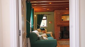 Ein gemütliches Wohnzimmer mit einem grünen Sofa, einem Kamin und einer Ziegelwand.