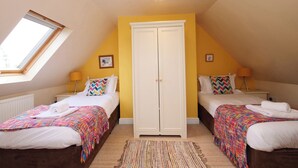 Ein Schlafzimmer mit zwei Betten, einem Kleiderschrank, einem Oberlicht und einem kleinen Fenster.