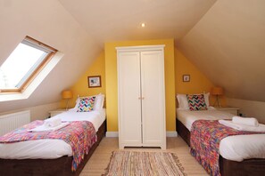 A bedroom with two beds, a wardrobe, a skylight, and a small window. - Chomley @ Summerfield Farm (Whitby)