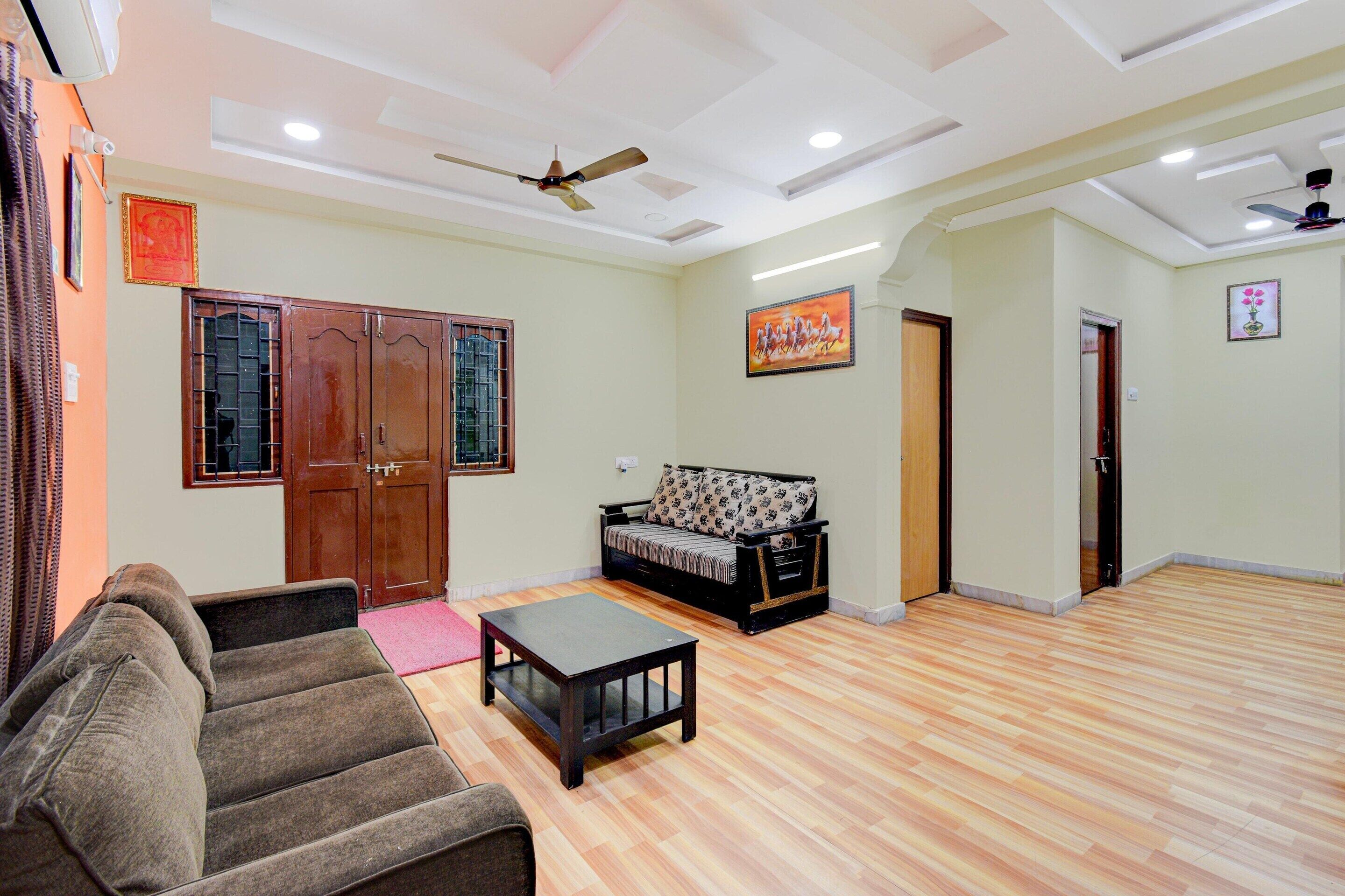 A living room with a sofa, a coffee table, a ceiling fan, and wooden flooring.